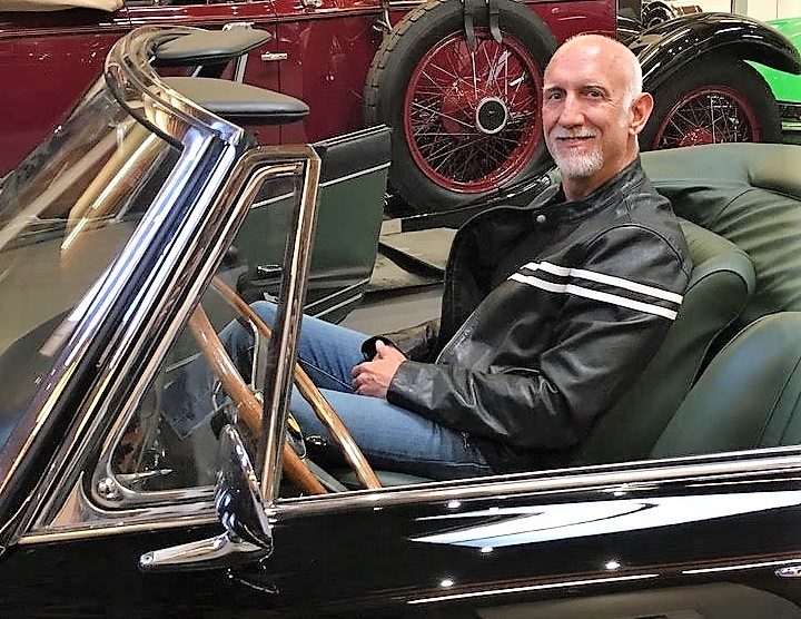 Brent Martini seated at the wheel of a restored vintage convertible