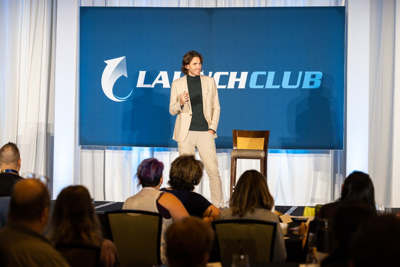Mentor Dida speaking on stage to a seated audience at a Launch Club event